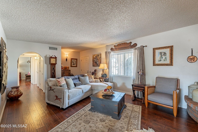 living area featuring visible vents, dark wood-type flooring, baseboards, arched walkways, and a textured ceiling