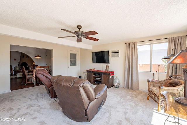 carpeted living room featuring a ceiling fan, baseboards, and a textured ceiling