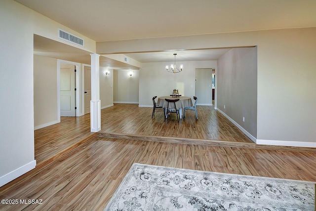 dining area with visible vents, baseboards, decorative columns, an inviting chandelier, and wood finished floors