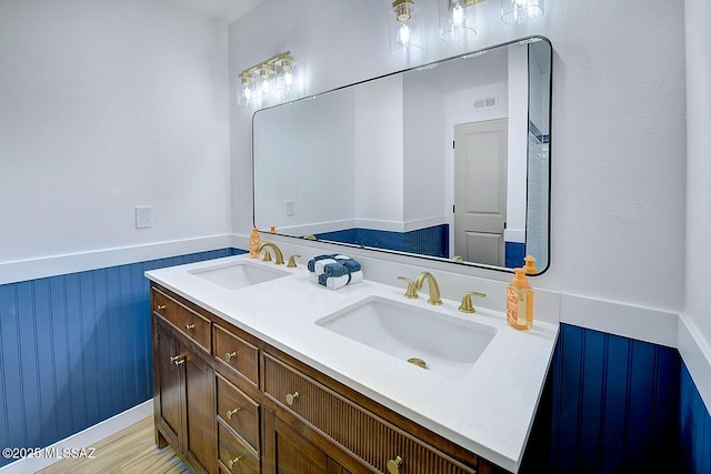 bathroom with visible vents, wainscoting, wood finished floors, and a sink