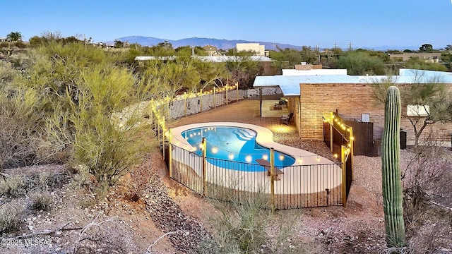 view of swimming pool with a patio area, fence, and a mountain view