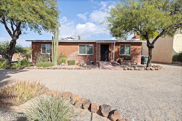 ranch-style house featuring brick siding and a chimney