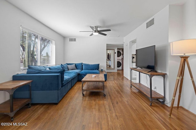 living room featuring light wood finished floors, visible vents, ceiling fan, and stacked washing maching and dryer