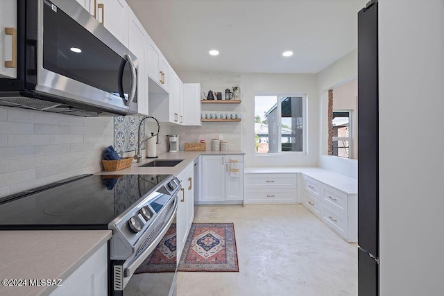 kitchen featuring tasteful backsplash, appliances with stainless steel finishes, white cabinetry, a sink, and open shelves