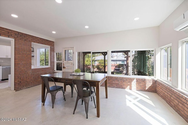 dining space featuring finished concrete floors, a wealth of natural light, a wall unit AC, and brick wall