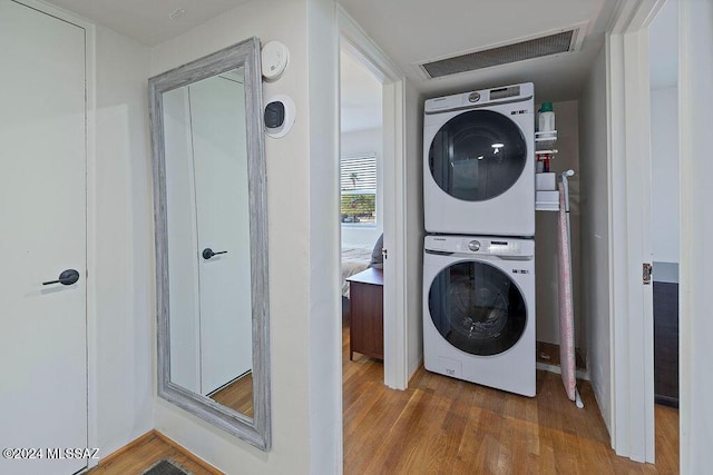 washroom featuring stacked washer / dryer, wood finished floors, laundry area, and visible vents