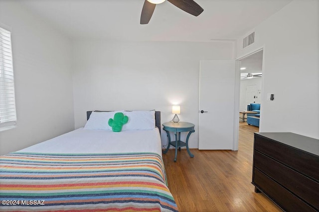 bedroom featuring ceiling fan, visible vents, and wood finished floors