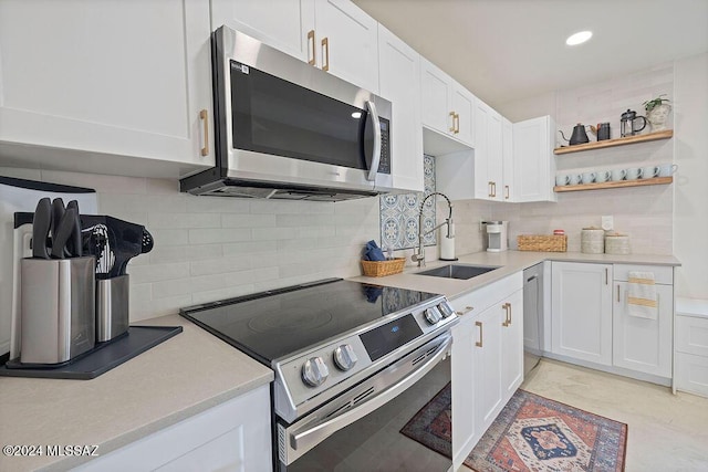 kitchen with light countertops, decorative backsplash, a sink, white cabinets, and appliances with stainless steel finishes