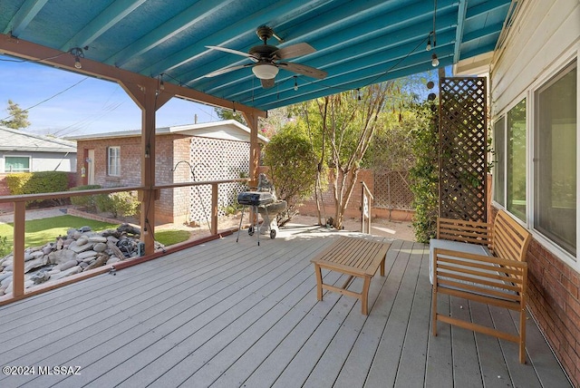 wooden deck with a ceiling fan, fence, and a grill