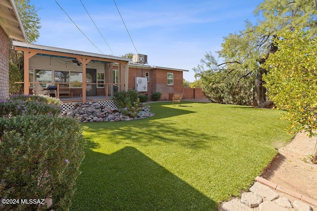 view of yard with fence, central AC unit, and a ceiling fan