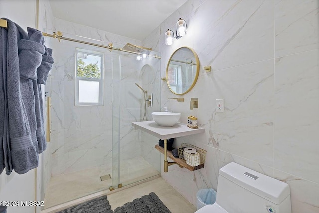 bathroom with a sink, toilet, tile walls, and a marble finish shower