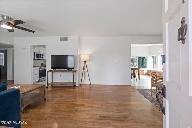 living area featuring visible vents, a ceiling fan, and wood finished floors