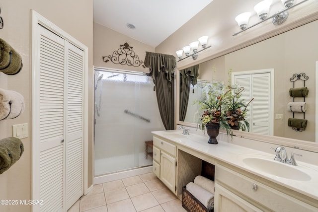 full bath with a sink, a closet, tile patterned flooring, and a stall shower