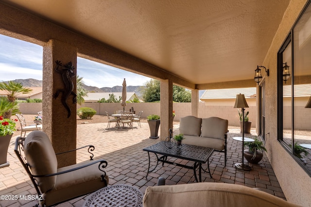 view of patio / terrace with an outdoor living space, outdoor dining area, a fenced backyard, and a mountain view