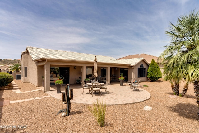 back of house with a tiled roof, a patio, and stucco siding