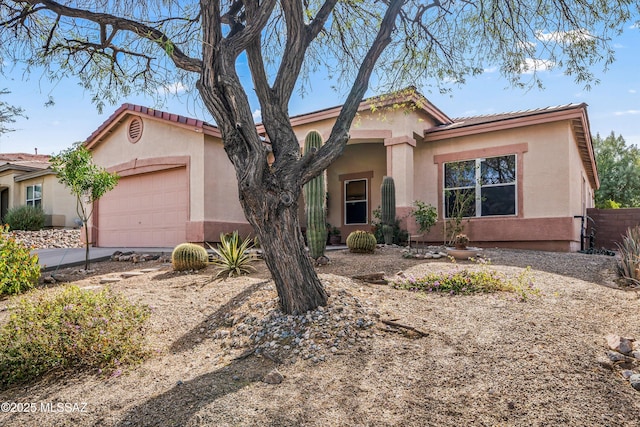 view of front of property featuring stucco siding, a garage, driveway, and fence