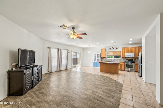 kitchen with visible vents, tasteful backsplash, open floor plan, stainless steel appliances, and a healthy amount of sunlight