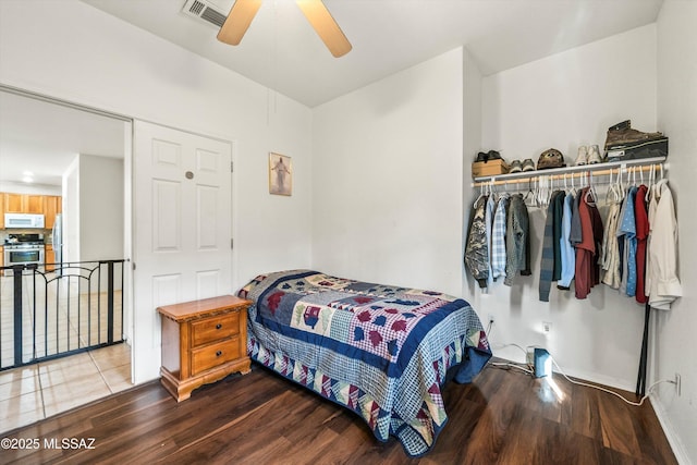 bedroom featuring visible vents, wood finished floors, freestanding refrigerator, a closet, and ceiling fan