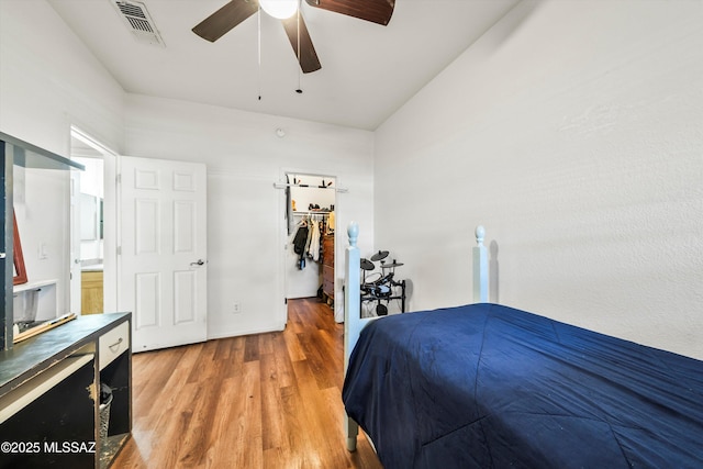 bedroom featuring visible vents, a walk in closet, light wood-style flooring, and a ceiling fan