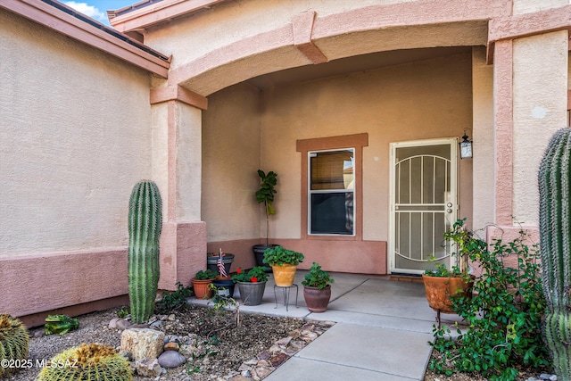 property entrance with stucco siding and a patio