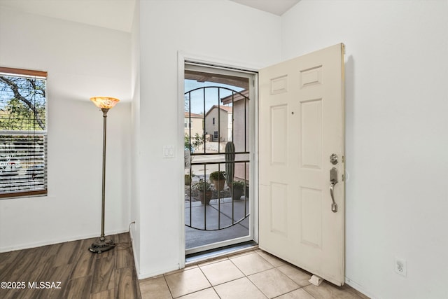 entryway with baseboards, plenty of natural light, and light tile patterned flooring