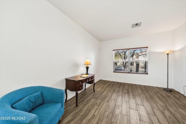 living area with visible vents, wood finished floors, and vaulted ceiling