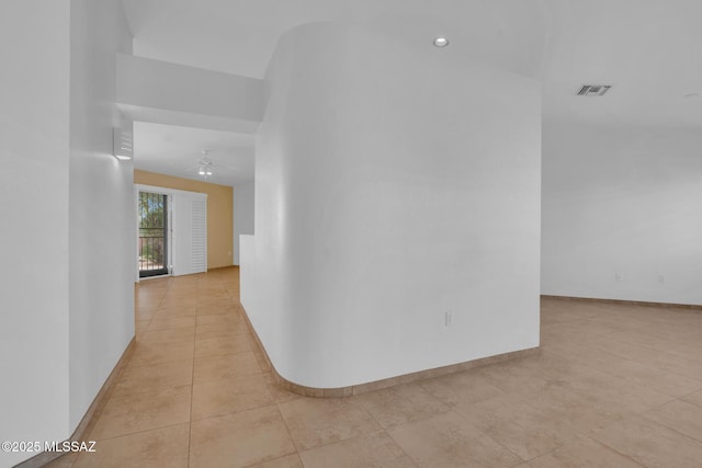 corridor featuring light tile patterned floors, visible vents, and baseboards