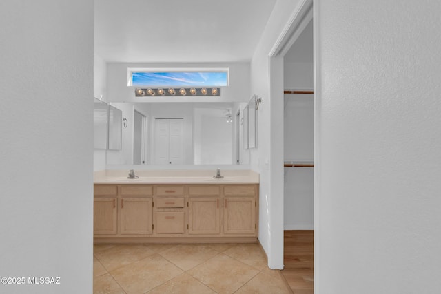 bathroom with a sink, a walk in closet, double vanity, and tile patterned floors