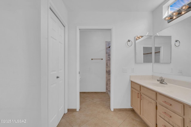 bathroom featuring tile patterned floors, baseboards, vanity, and a closet