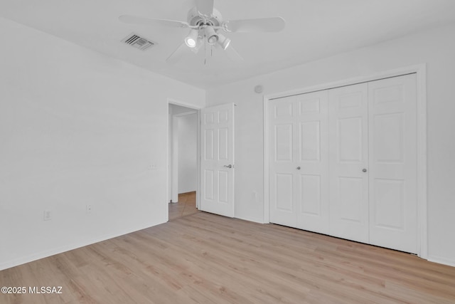 unfurnished bedroom featuring a closet, visible vents, ceiling fan, and wood finished floors