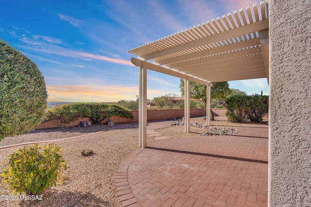 patio terrace at dusk with a fenced backyard and a pergola