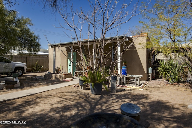 rear view of house featuring a patio, fence, and stucco siding