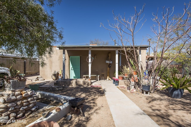 rear view of property featuring fence and stucco siding