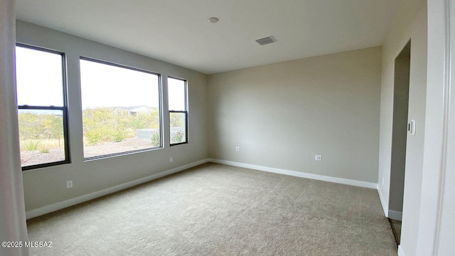 carpeted spare room featuring visible vents and baseboards