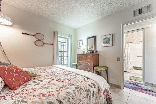 bedroom with tile patterned floors, visible vents, a textured ceiling, and baseboards