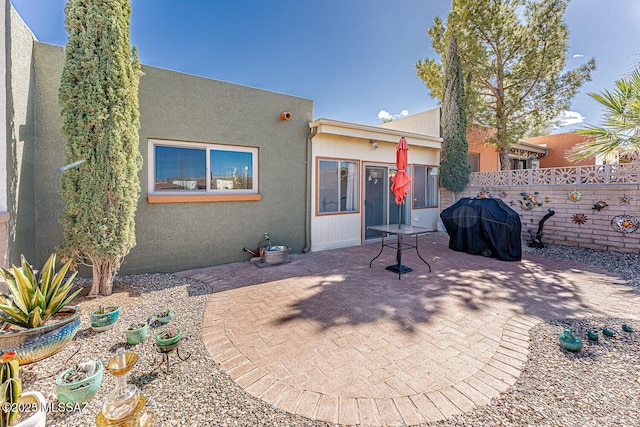 rear view of property with stucco siding, a patio, and fence