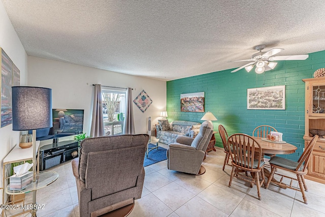 living area with an accent wall, light tile patterned floors, a ceiling fan, and a textured ceiling