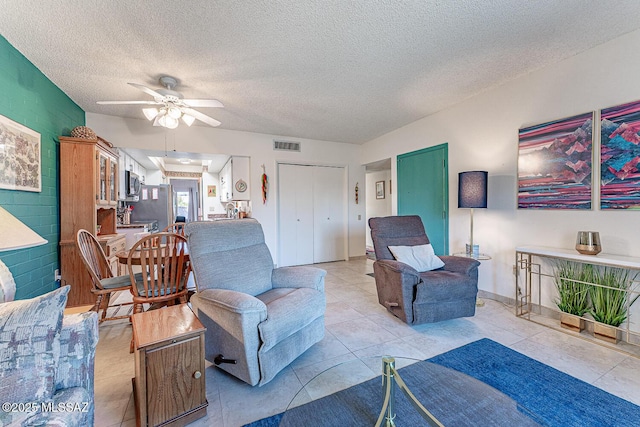 living area featuring visible vents, a textured ceiling, and ceiling fan