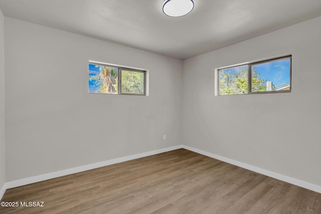 unfurnished room with a wealth of natural light, baseboards, and wood finished floors