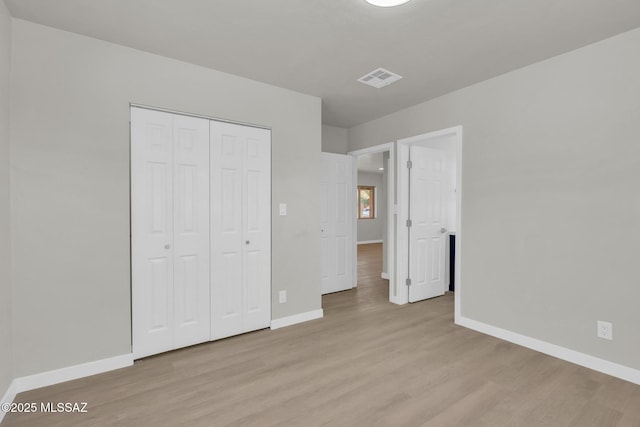 unfurnished bedroom featuring wood finished floors, visible vents, and baseboards