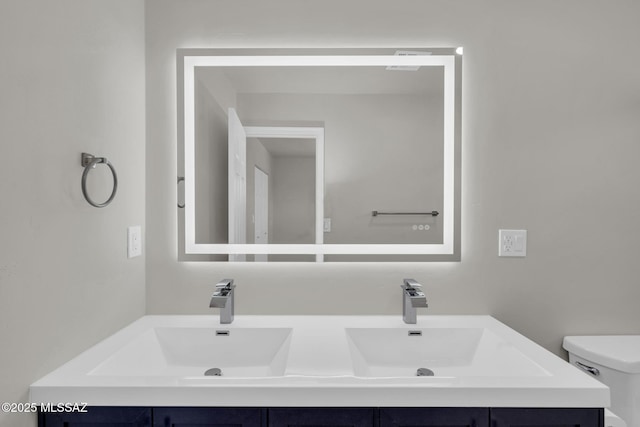 bathroom featuring double vanity, toilet, and a sink