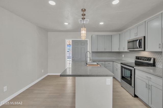 kitchen featuring visible vents, light wood-type flooring, a sink, appliances with stainless steel finishes, and decorative backsplash