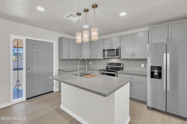 kitchen with visible vents, gray cabinets, a sink, light wood-style floors, and appliances with stainless steel finishes