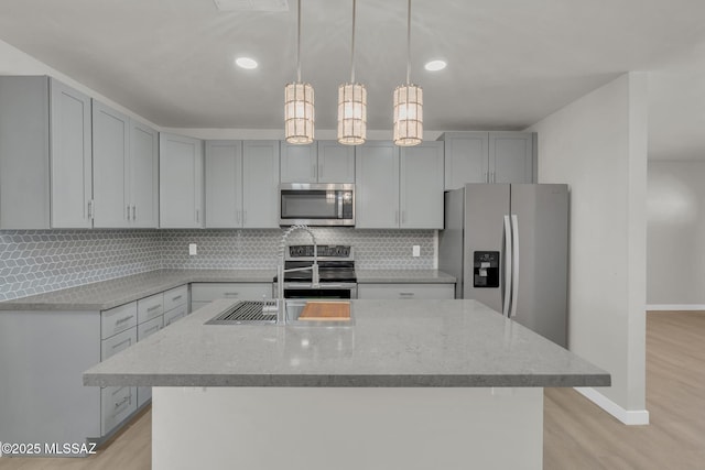 kitchen featuring decorative backsplash, light stone countertops, gray cabinets, and appliances with stainless steel finishes