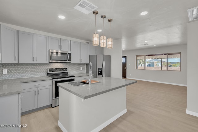 kitchen featuring stainless steel appliances, tasteful backsplash, visible vents, and light wood-style flooring