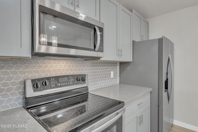 kitchen with tasteful backsplash, white cabinets, stainless steel appliances, and baseboards