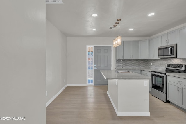 kitchen featuring a sink, gray cabinets, light wood finished floors, and stainless steel appliances