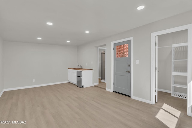 interior space featuring recessed lighting, light wood-style flooring, baseboards, and a sink