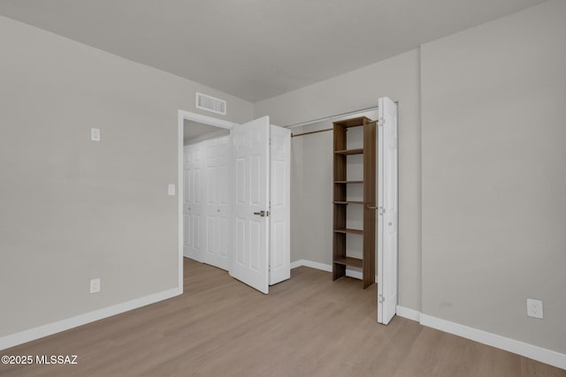 unfurnished bedroom with light wood-style floors, visible vents, a closet, and baseboards