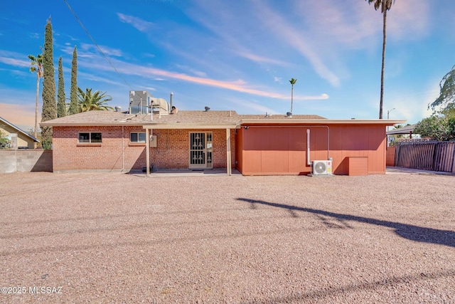 rear view of property featuring ac unit, brick siding, and fence